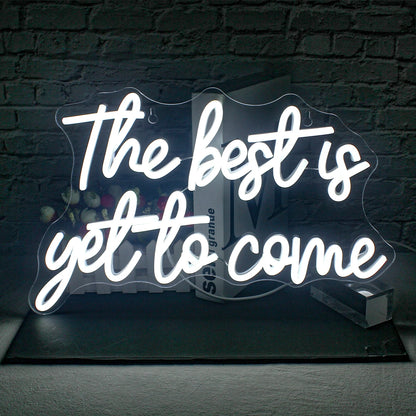 The image showcases a vibrant, handmade LED neon sign that reads "The Best is Yet to Come" in a stylish, cursive font.