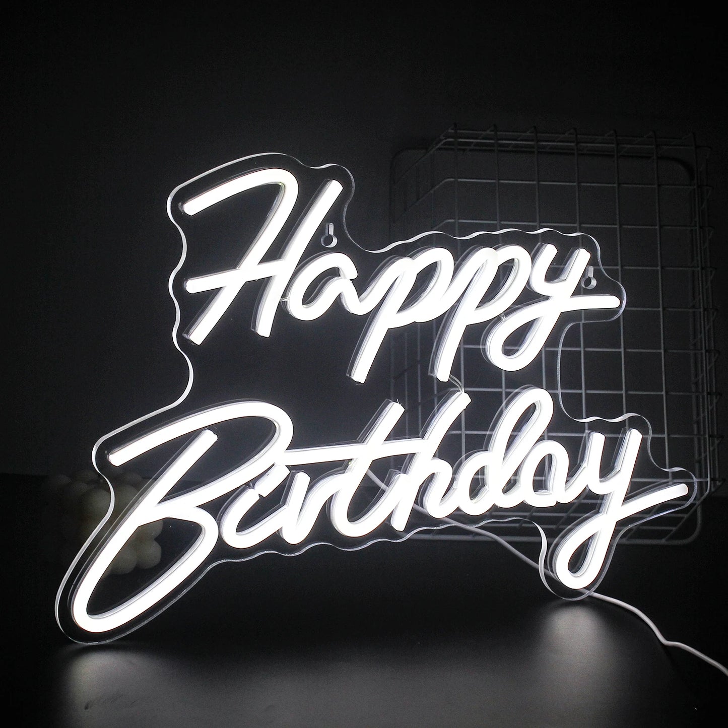 A vibrant "Happy Birthday" LED neon sign glowing warmly against a dark background.
