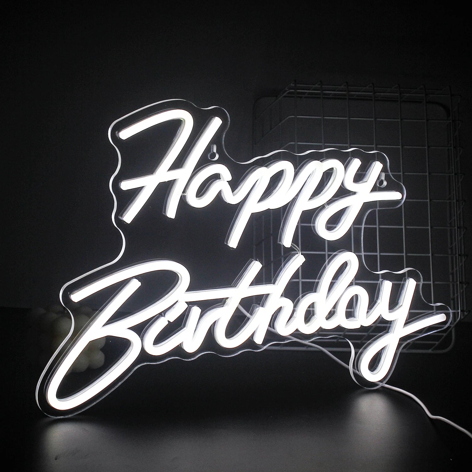 A vibrant "Happy Birthday" LED neon sign glowing warmly against a dark background.