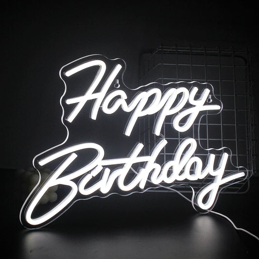 A vibrant "Happy Birthday" LED neon sign glowing warmly against a dark background.