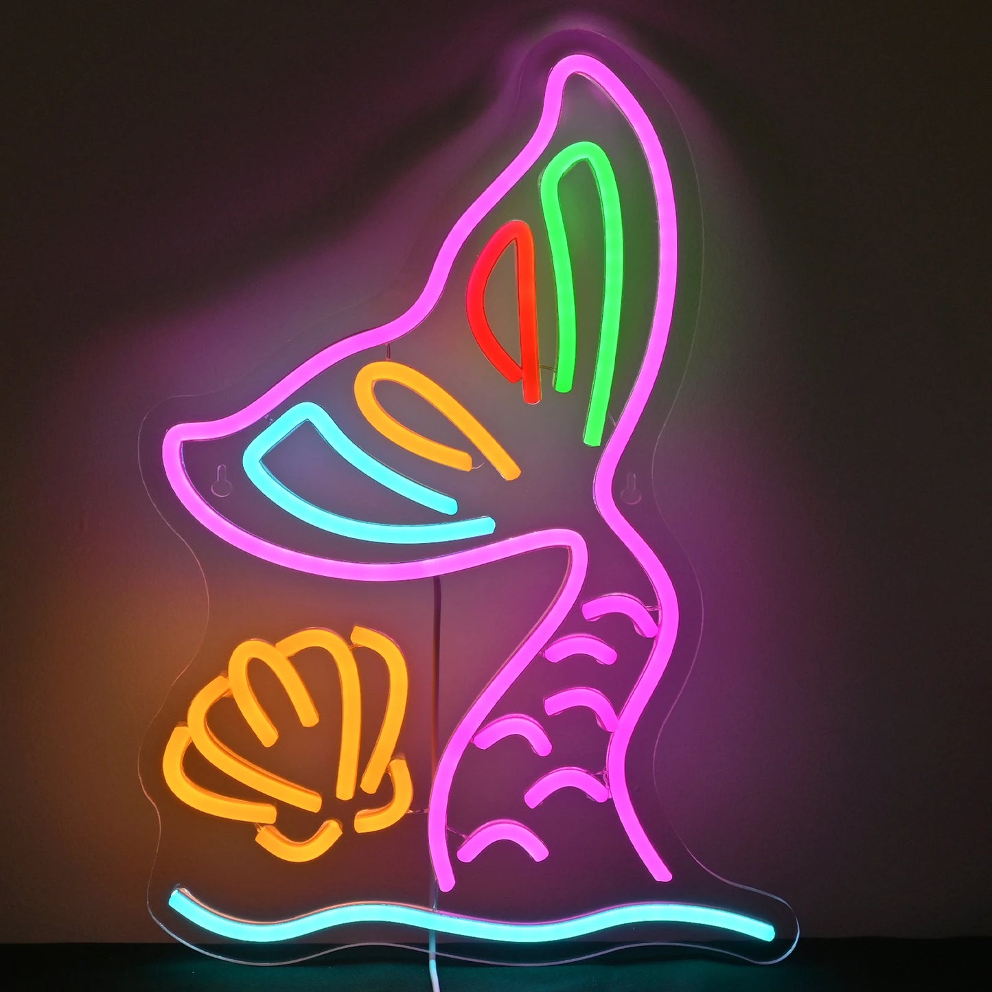 The image features a vibrant LED neon sign in the shape of a mermaid tail.