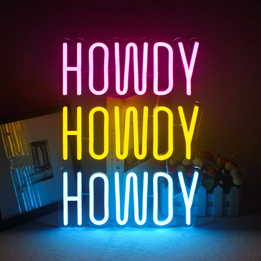 A vibrant, handmade LED neon sign displaying the word "Howdy" in a playful, cursive font.