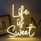 A imagem apresenta um letreiro de LED neon vibrante, feito à mão, em cores brilhantes e luminosas, que diz a frase "A vida é doce".