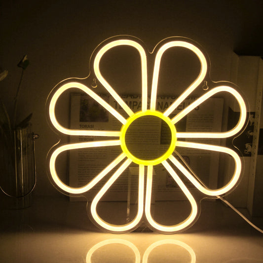 The image displays a vibrant LED neon sign in the shape of a flower.