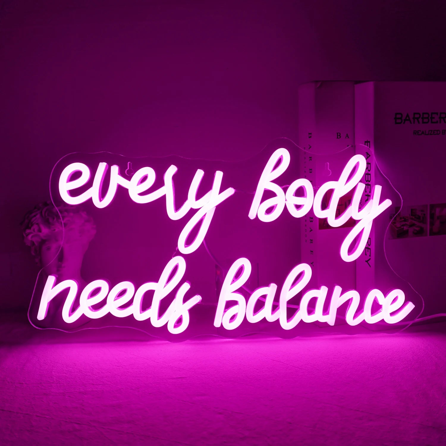 The image displays a vibrant "Every Body Needs Balance" LED neon sign.