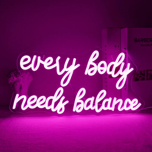 A imagem exibe uma vibrante placa de LED neon com os dizeres "Todo Corpo Precisa de Equilíbrio".