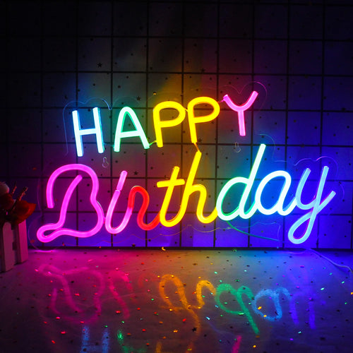 Uma vibrante placa de LED neon com os dizeres "Feliz Aniversário" em cores festivas montada na parede.