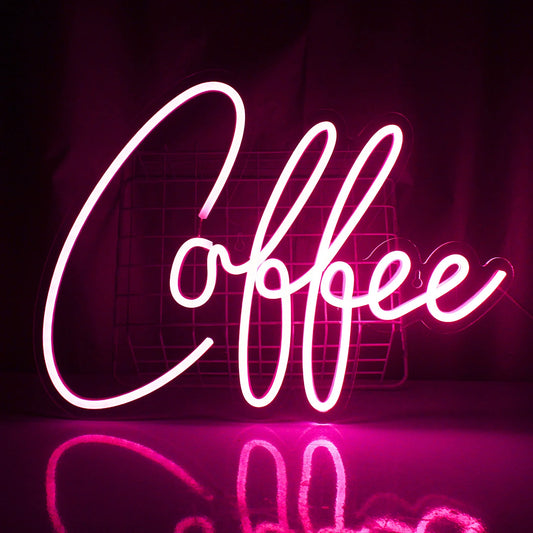 The image displays a vibrant LED neon sign in the shape of a steaming coffee cup.