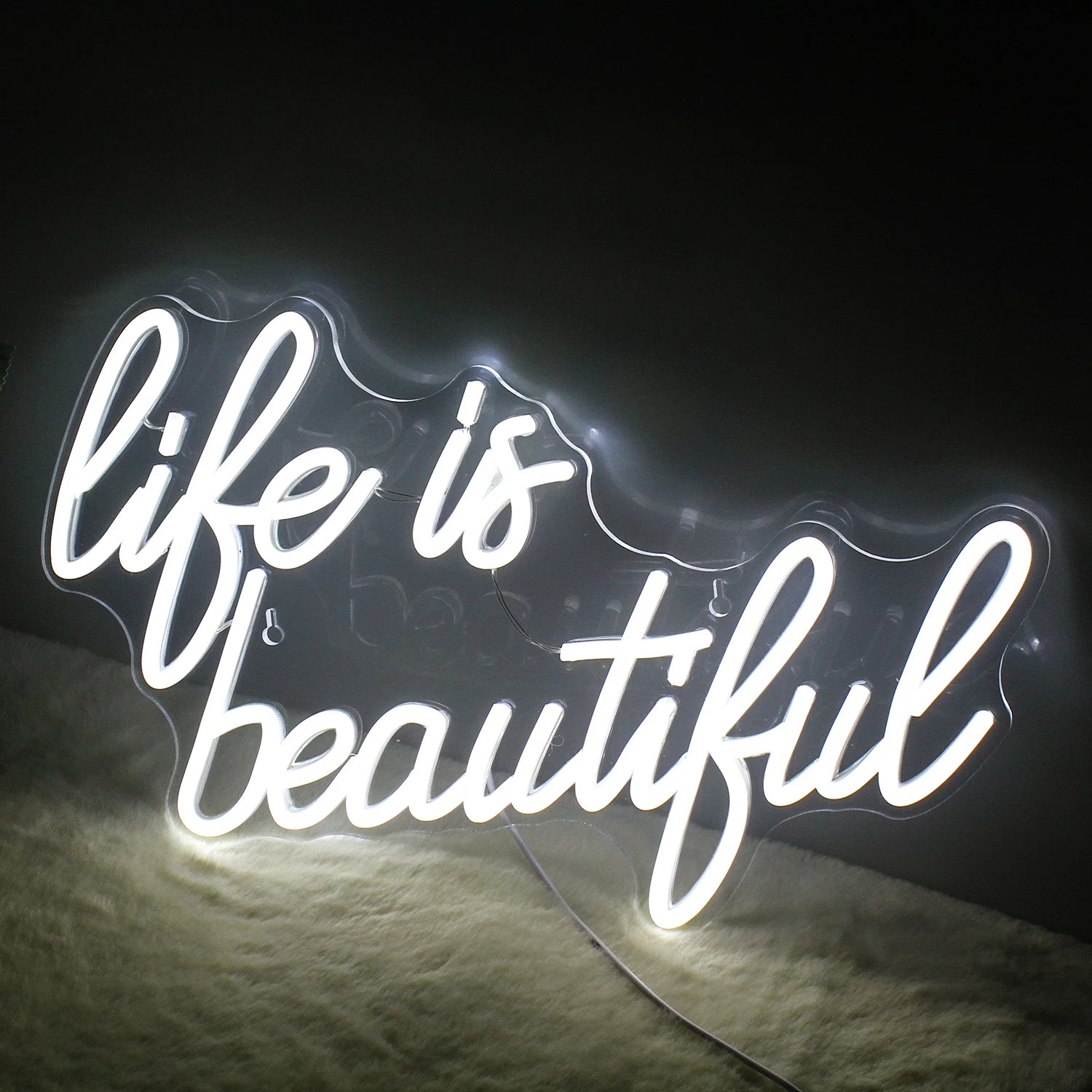 A vibrant, handmade LED neon sign displaying the phrase "Life is Beautiful" in elegant, flowing script.