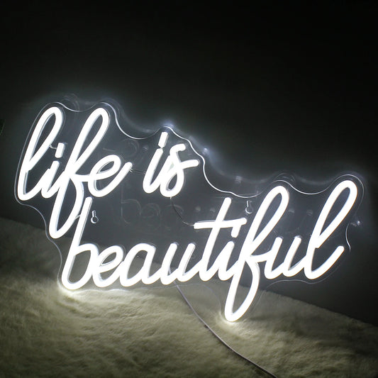 A vibrant, handmade LED neon sign displaying the phrase "Life is Beautiful" in elegant, flowing script.
