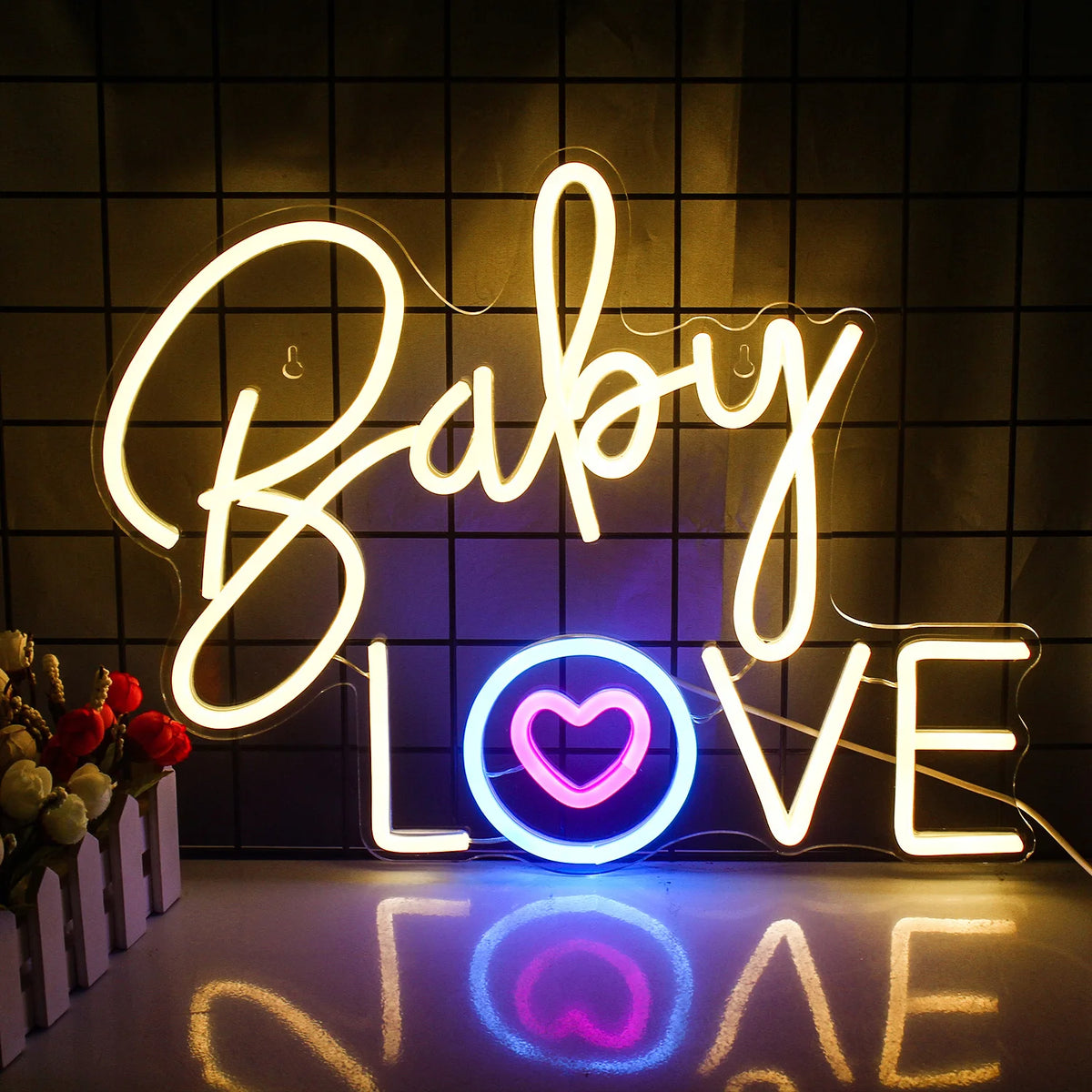 Uma vibrante placa de neon rosa soletra as palavras "Baby Love" em uma fonte divertida e cursiva.