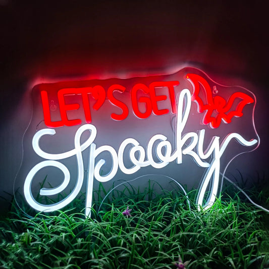 The image features a vibrant LED neon sign displaying the words "Let's Get Spooky" in a bold, quirky font.