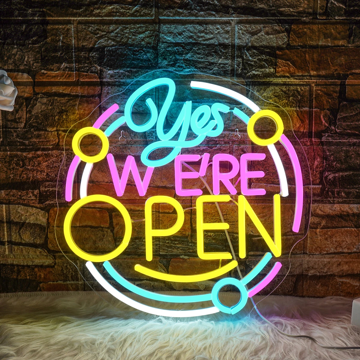 A imagem mostra uma placa de LED neon vibrante exibindo a mensagem "Sim, estamos abertos.