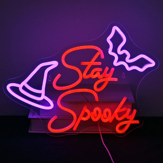 The image features a handcrafted LED neon sign displaying the words "Stay Spooky" in a playful, flowing script.