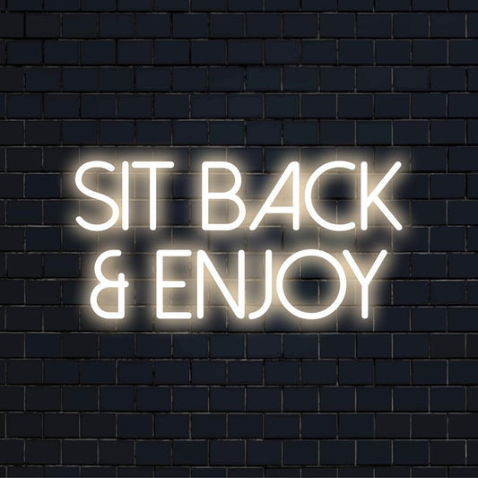 Custom LED neon sign reading Sit Back And Enjoy in bright hues, perfect for enhancing relaxation spaces and lounge areas.