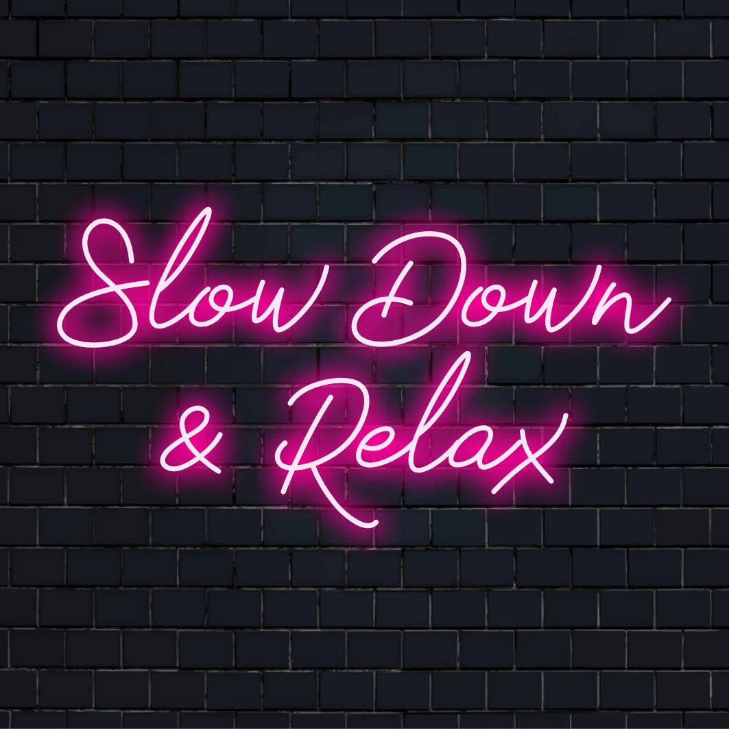 Placa de neon LED exibindo as palavras "Desacelere e relaxe"; uma peça de decoração neon suave e feita sob medida para um ambiente tranquilo.