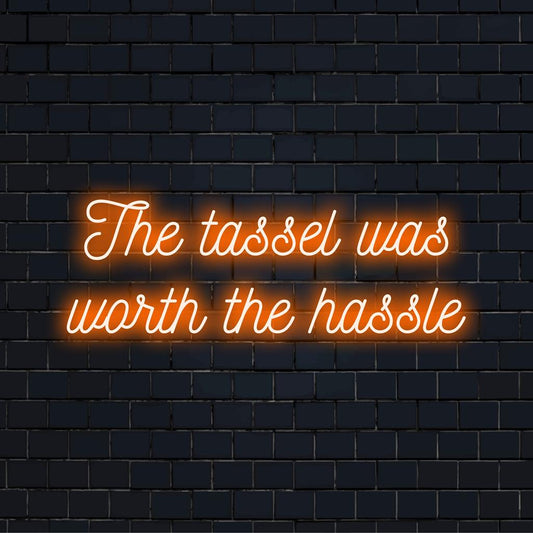 Custom made LED neon sign showcasing the phrase: The Tassel Was Worth The Hassle. A celebratory neon quote art piece.