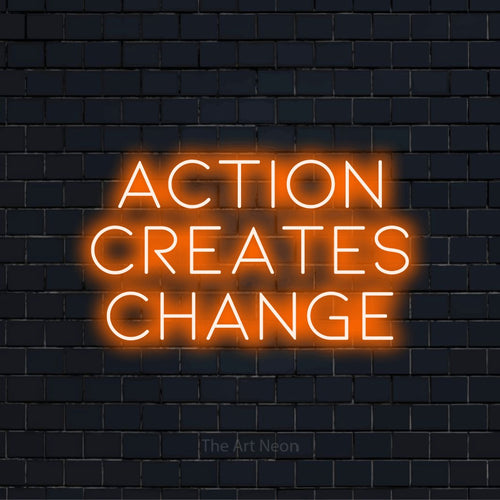 "Action Creates Change" neon text design on a black brick wall
