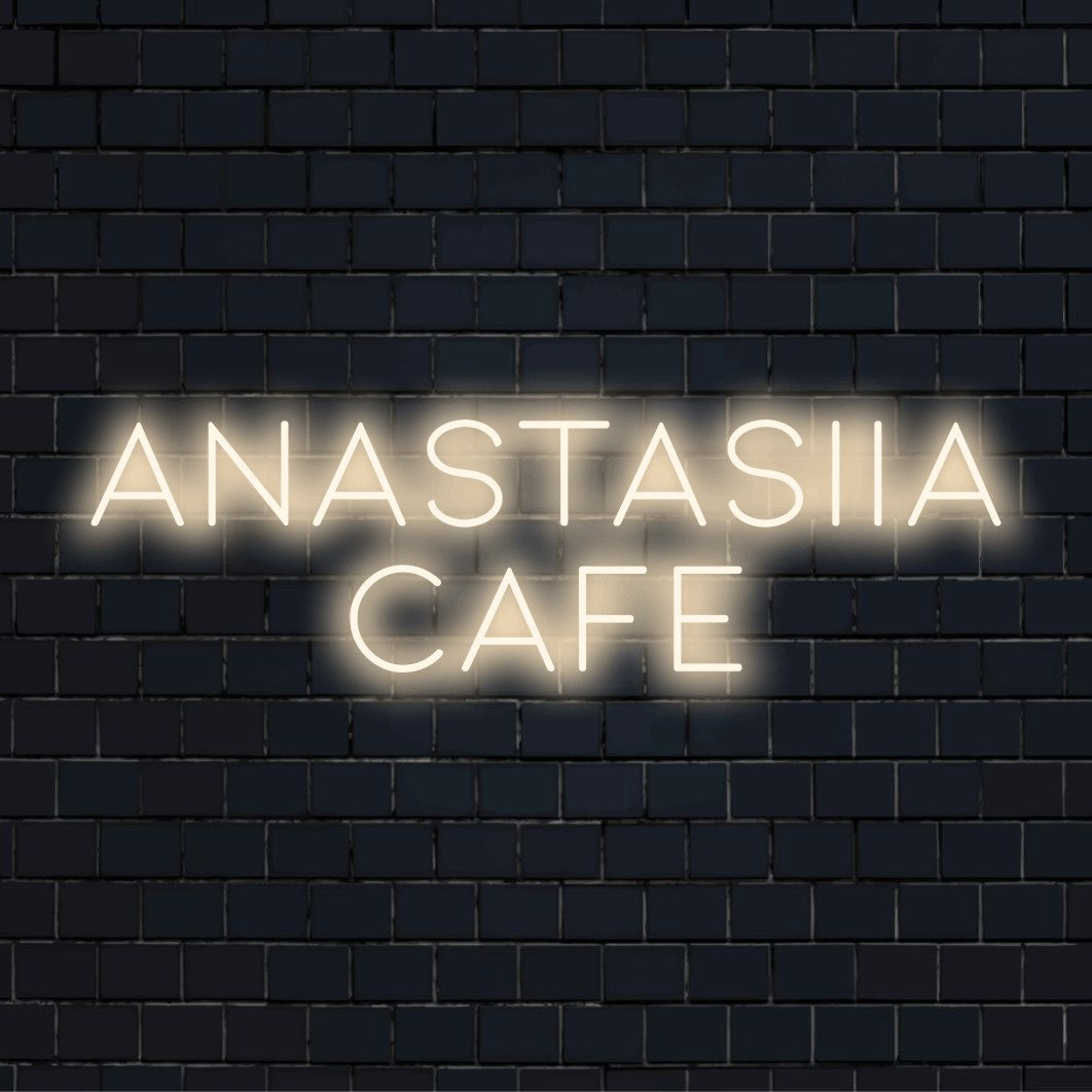 Anastasiia Cafe Personalized LED Neon Sign, glowing lettering against black brick wall