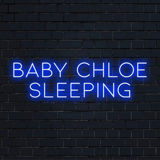 Baby Chloe Sleeping Personalized LED Neon Sign, bright neon lettering against black brick wall