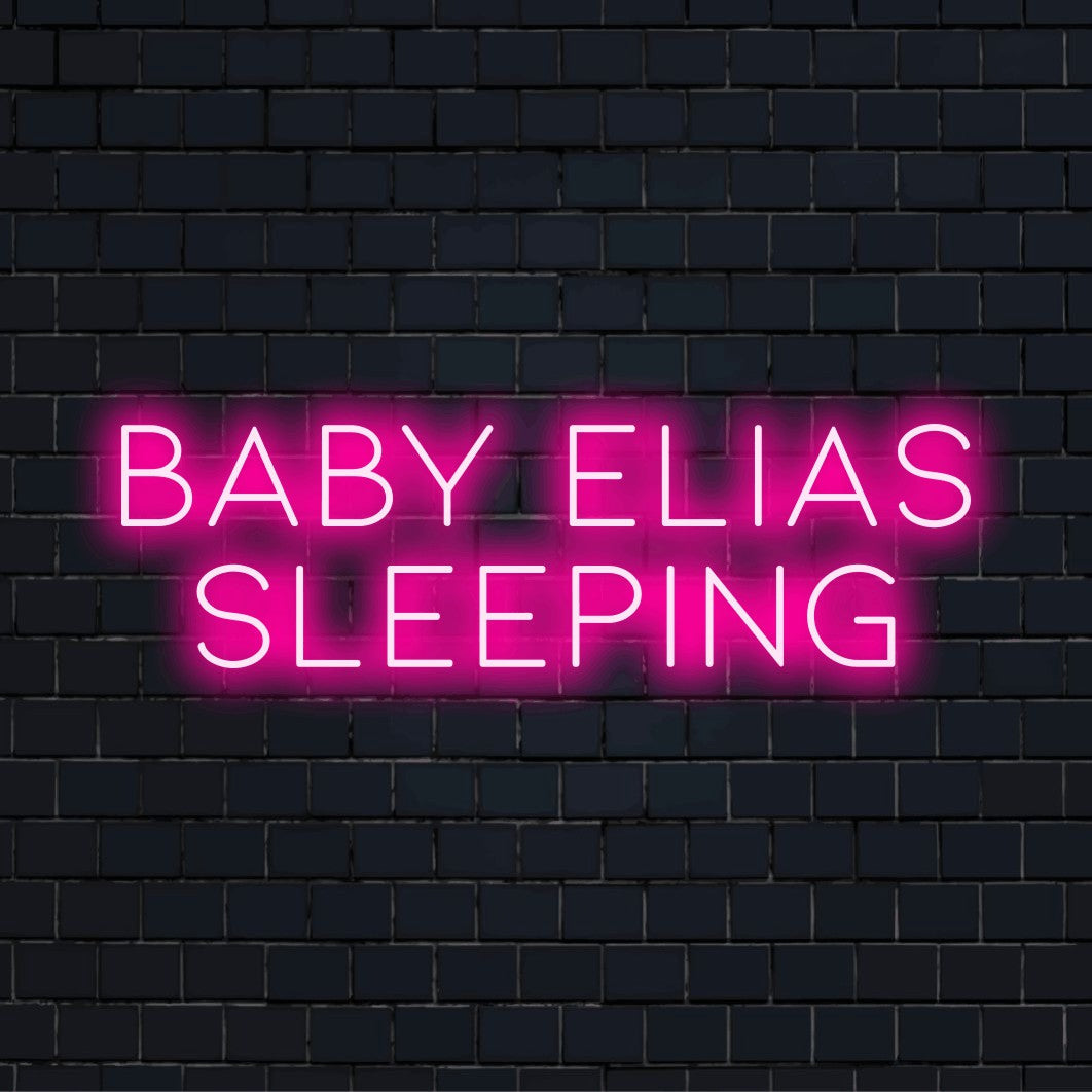Baby Elias Sleeping Personalized LED Neon Sign, bright neon lettering against black brick wall