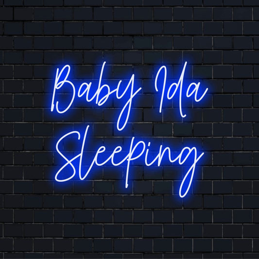Baby Ida Sleeping Personalized Neon Light with glowing wall decor against black brick wall