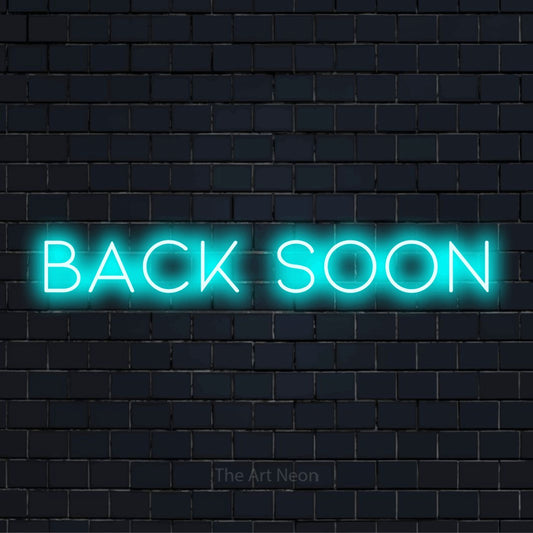 "Back Soon" LED neon sign on a black brick wall