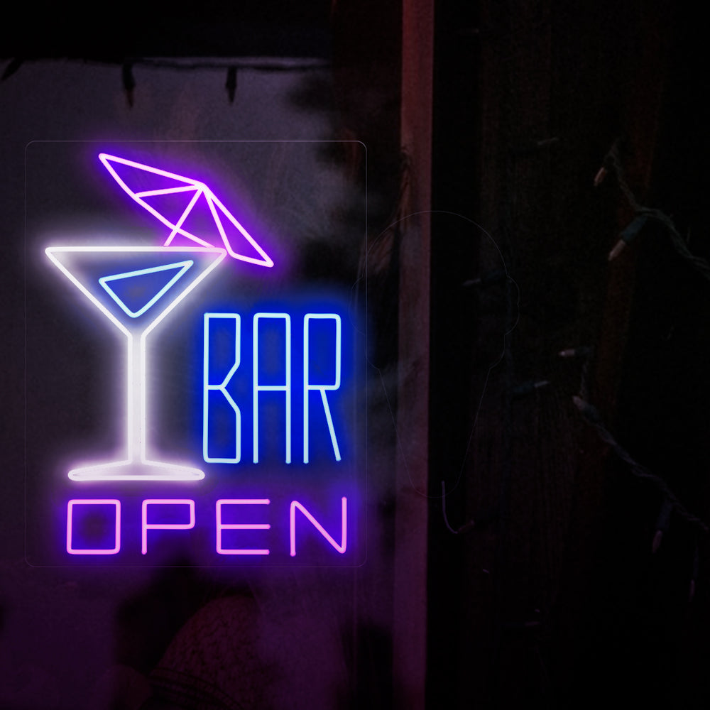 A foto mostra um letreiro de neon com um coquetel com guarda-chuva à esquerda e o texto "open bar" à direita. Este letreiro de neon é ideal para bares, tanto internos quanto externos.