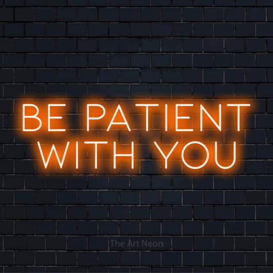 "Be Patient With You" neon text design on a black brick wall