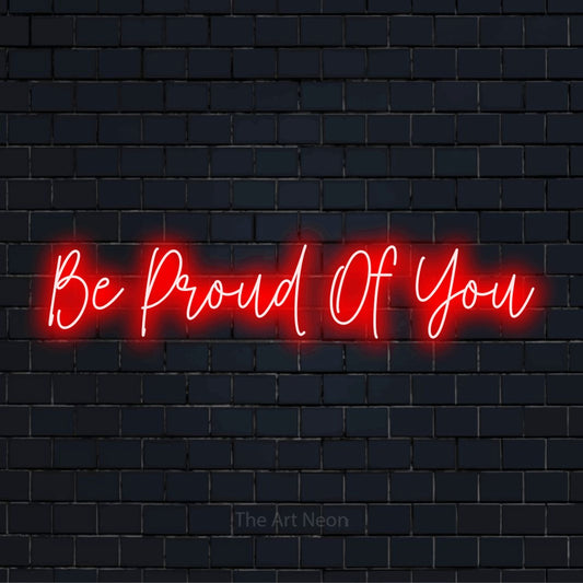 "Be Proud Of You" glowing LED neon sign on a black brick wall