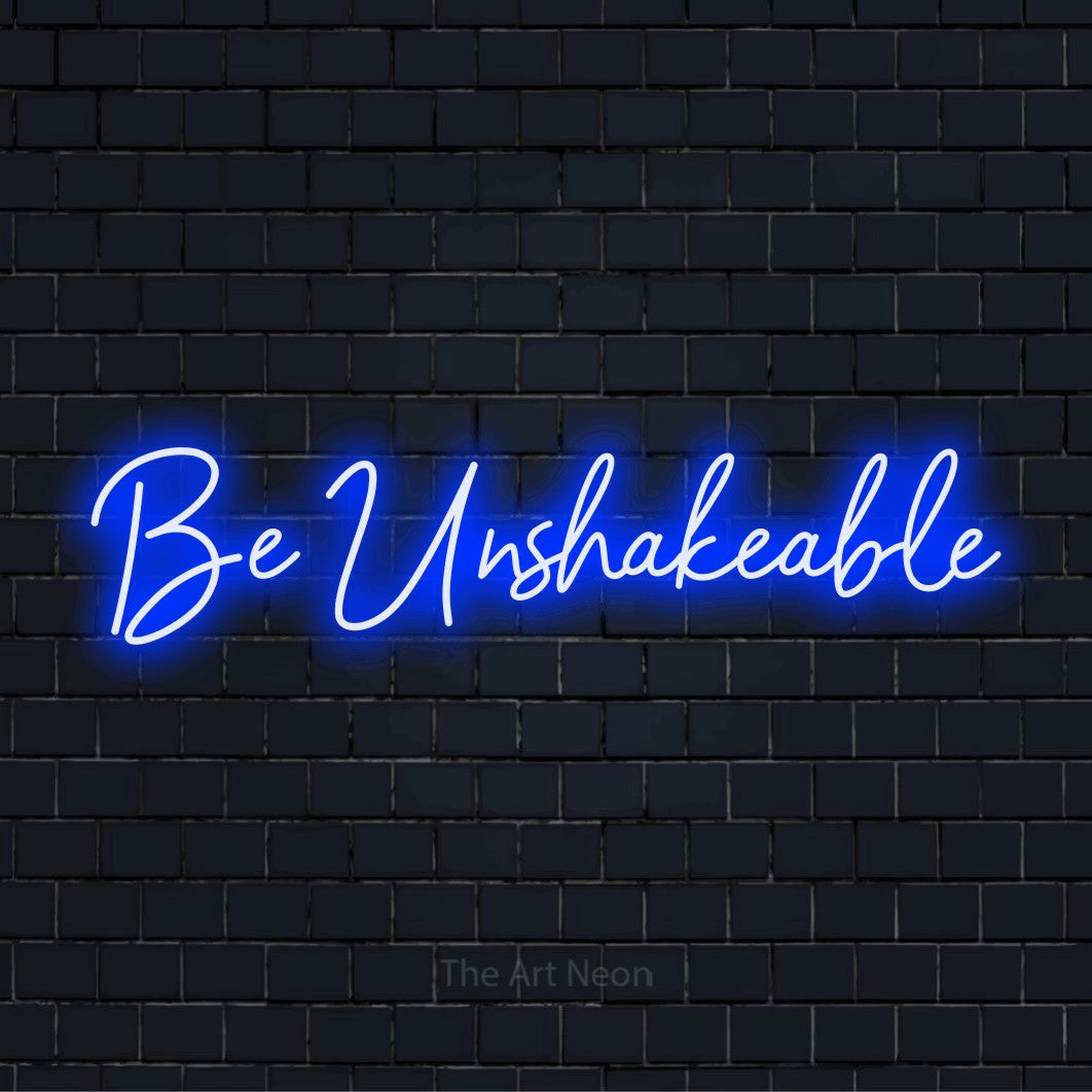 "Be Unshakeable" text design with neon effect on a black brick wall