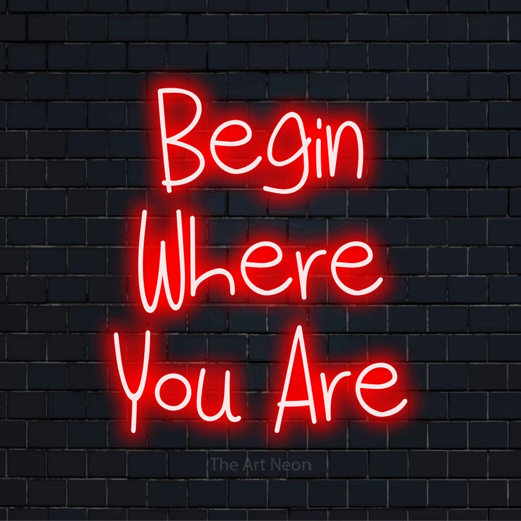 "Begin Where You Are" neon text design on a black brick wall
