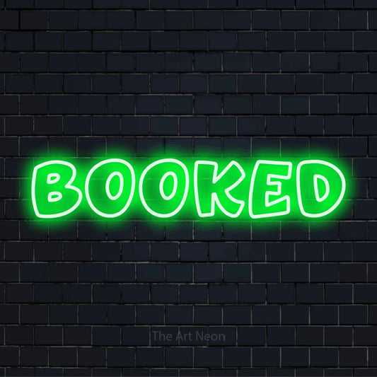 "Booked" script-style LED neon sign on a black brick wall