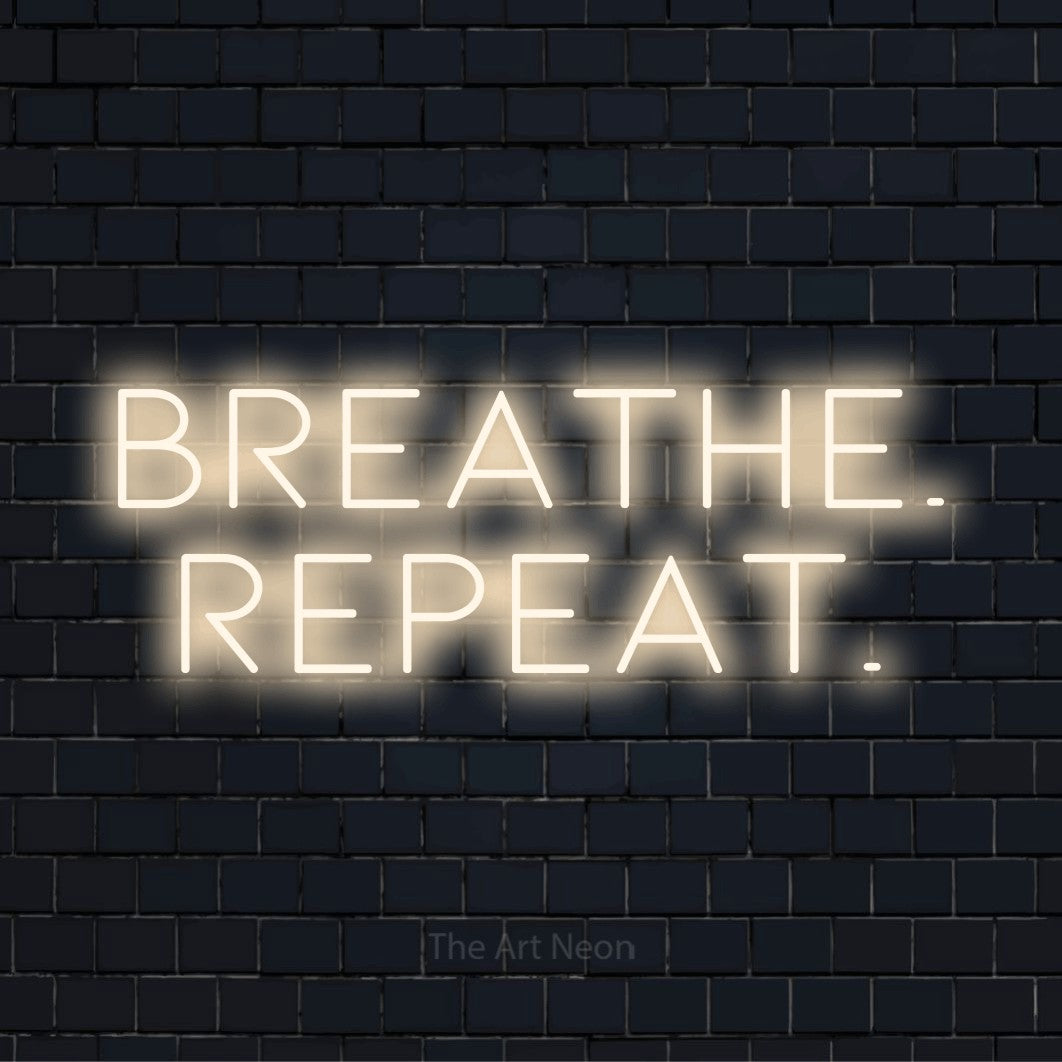 "Breathe. Repeat." neon text design on a black brick wall