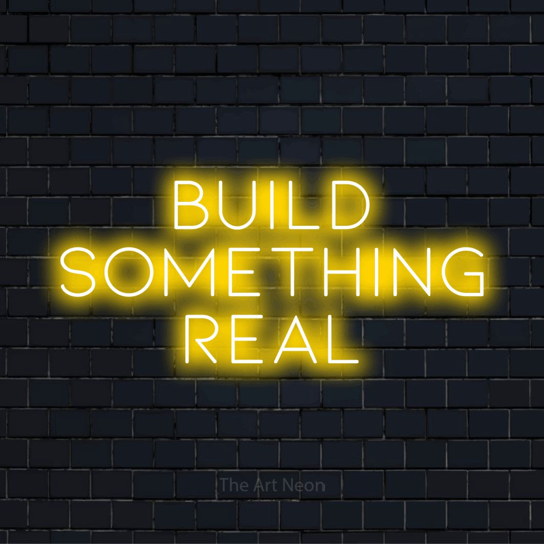 "Build Something Real" glowing LED neon sign on a black brick wall
