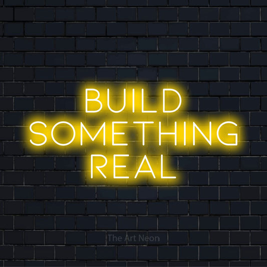 "Build Something Real" glowing LED neon sign on a black brick wall