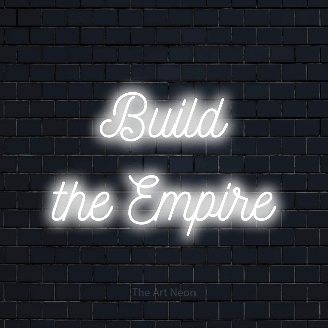 "Build The Empire" script-style LED neon sign on a black brick wall