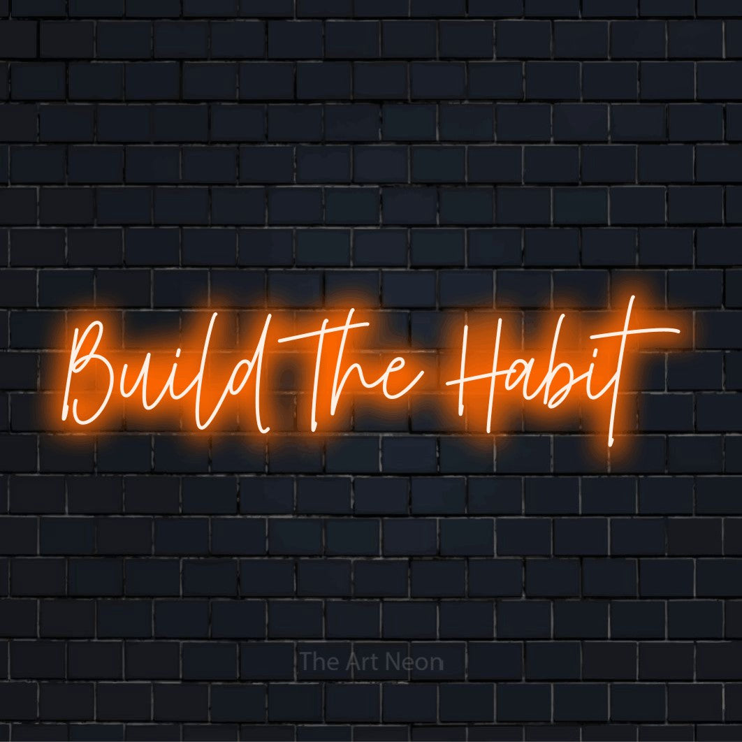 "Build The Habit" LED neon sign on a black brick wall