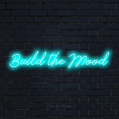 "Build The Mood" neon text design on a black brick wall
