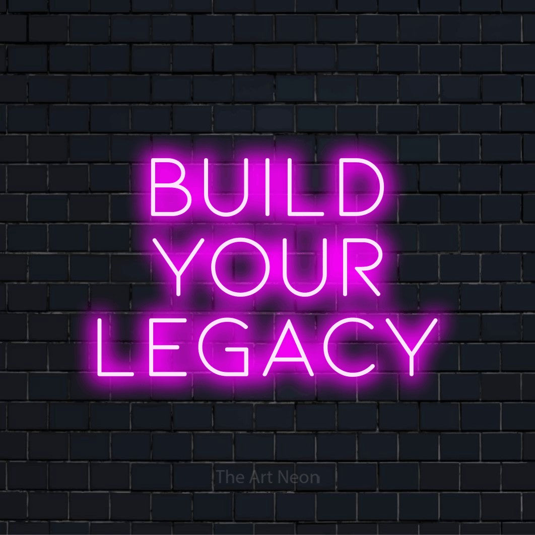 "Build Your Legacy" script-style LED neon sign on a black brick wall