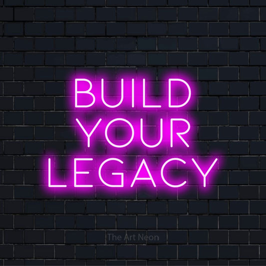 "Build Your Legacy" script-style LED neon sign on a black brick wall