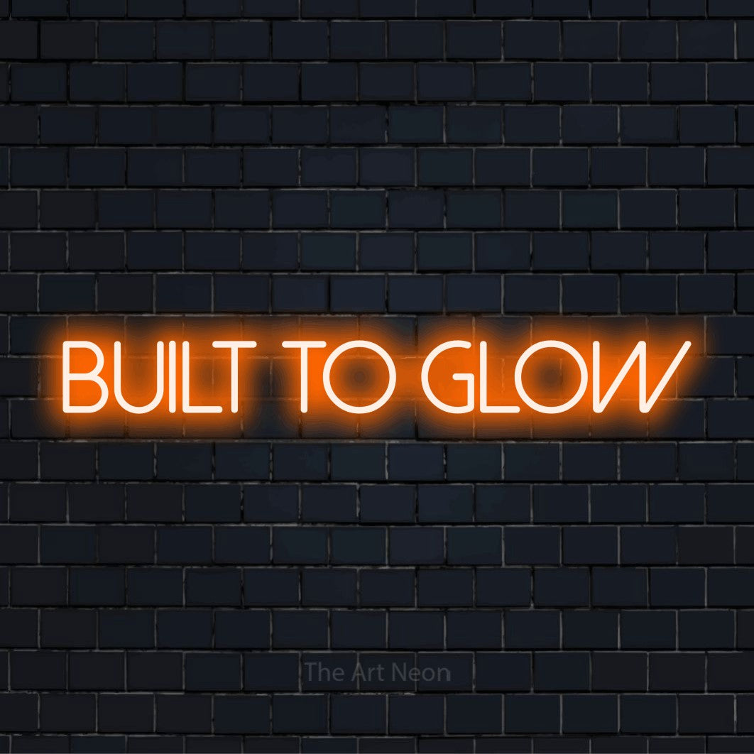 "Built To Glow" text design with neon effect on a black brick wall