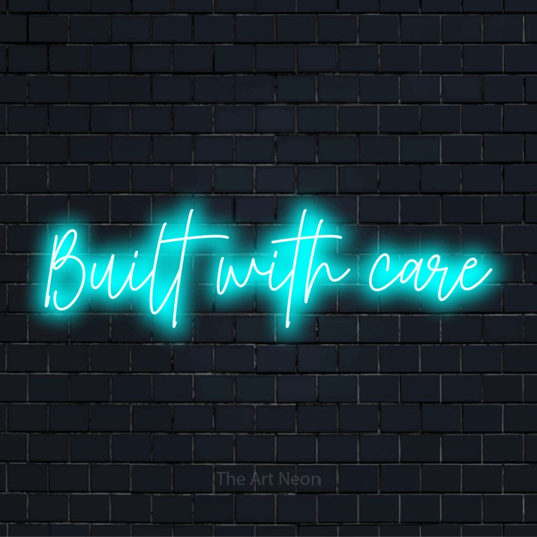 "Built With Care" script-style LED neon sign on a black brick wall