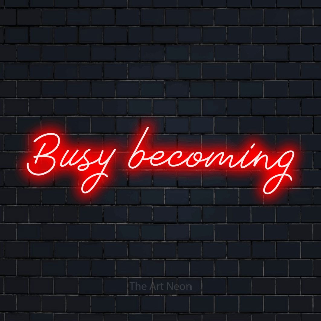 "Busy Becoming" LED neon sign on a black brick wall