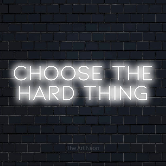 "Choose The Hard Thing" LED neon sign on a black brick wall