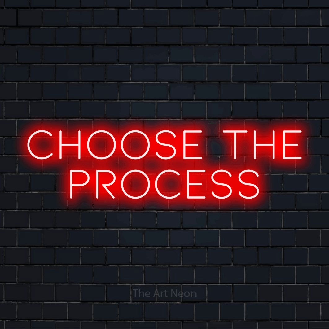"Choose The Process" glowing LED neon sign on a black brick wall