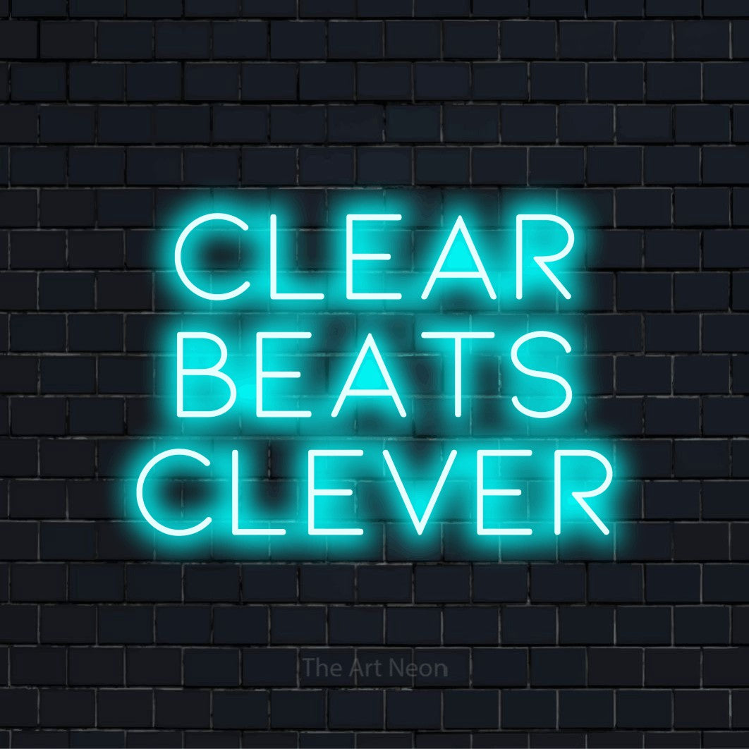 "Clear Beats Clever" text design with neon effect on a black brick wall