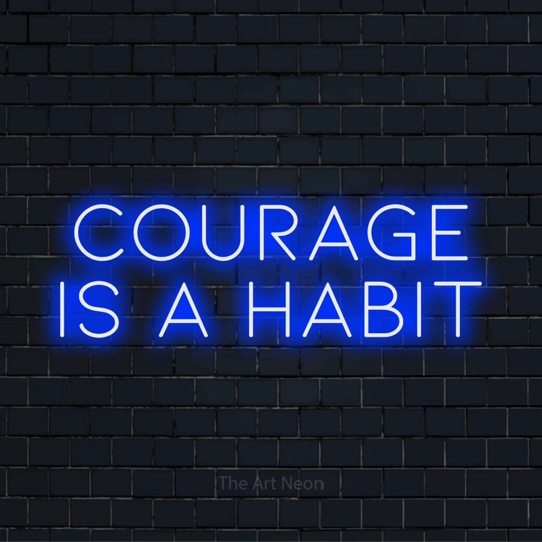 "Courage Is A Habit" glowing LED neon sign on a black brick wall