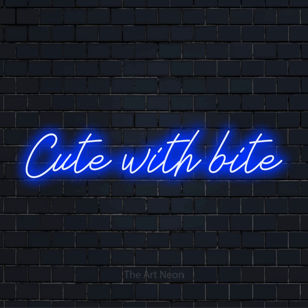 "Cute With Bite" script-style LED neon sign on a black brick wall