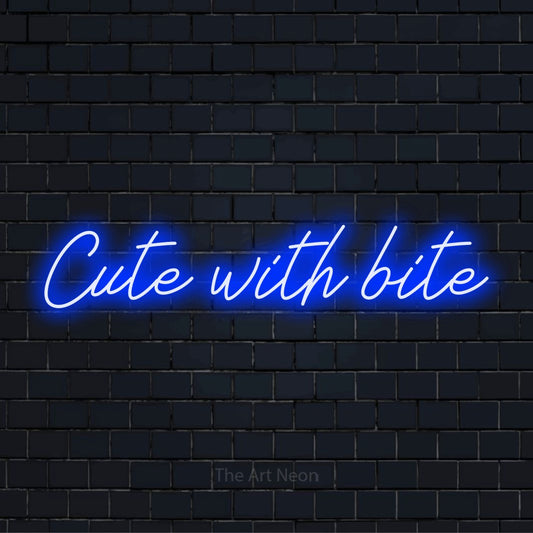 "Cute With Bite" script-style LED neon sign on a black brick wall